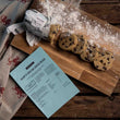 Load image into Gallery viewer, Cut Ready-To-Bake Welsh Cake Dough on a wooden surface with a welsh dragon patterned cloth with recipe.