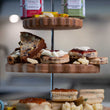 Load image into Gallery viewer, Three-tiered wooden dessert tower with welsh afternoon ingredients, bara brith, jam, welsh cakes, welsh cheese with a blurred background.