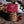 Packaged Cherry Bakewell Welsh Cakes with a MamGu Welshcakes Red label with loose welsh cakes, rolling pin, flour and fairy lights in the background.