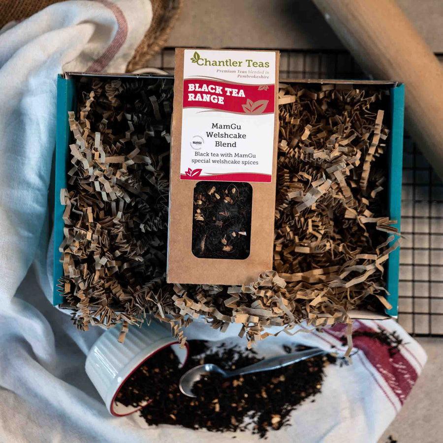 chantler teas mamgu welsh cake blend loose leaf tea in a cardbard box on a tea cloth next to loose tea and welsh cakes