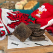 Load image into Gallery viewer, 4 Back Velvet Welsh Cakes on a wooden chopping board surrounded (red, white and green)
