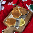Load image into Gallery viewer, Lemon Welsh Cakes daffodil shaped on a wooden chopping board
