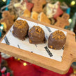 Load image into Gallery viewer, Three chocolate lotus welsh cake balls on a wooden board with a blurred background
