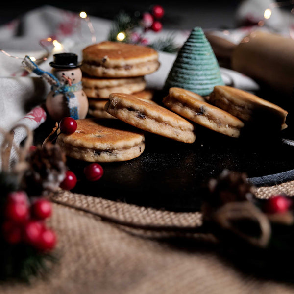 Mince Pie Welsh Cakes on a bakestone surrounded by Christmas decorations