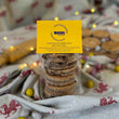 Load image into Gallery viewer, Mini Egg Welsh Cakes in a pack with a yellow label. The table has a table cloth with welsh dragons on it and in the background is a wooden rolling pin, loose mini eggs and welsh cakes
