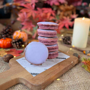 Stack of Purple Parma Violets Welsh Cakes on a wooden board with Autumn-themed decorations in the background.