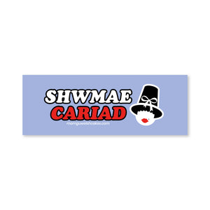A rectangular light purple sticker or decal with the text 'SHWMAE CARIAD' in white and red, plus a stylized cartoon welsh lady face wearing a black hat and red lips.
