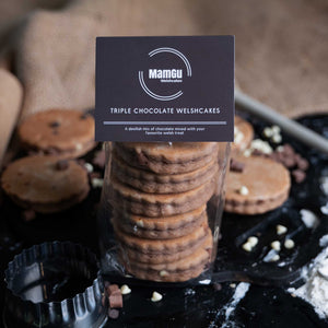 Packaged Triple Chocolate Welsh Cakes with a MamGu Welshcakes label on a rustic background with a welsh cake cutter in the foreground. 