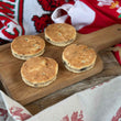 Load image into Gallery viewer, 4 Traditional Welsh Cakes on a wooden chopping board surrounded by a welsh dragons table coth, welsh scarf (red white and green) and a welsh rugby shirt.
