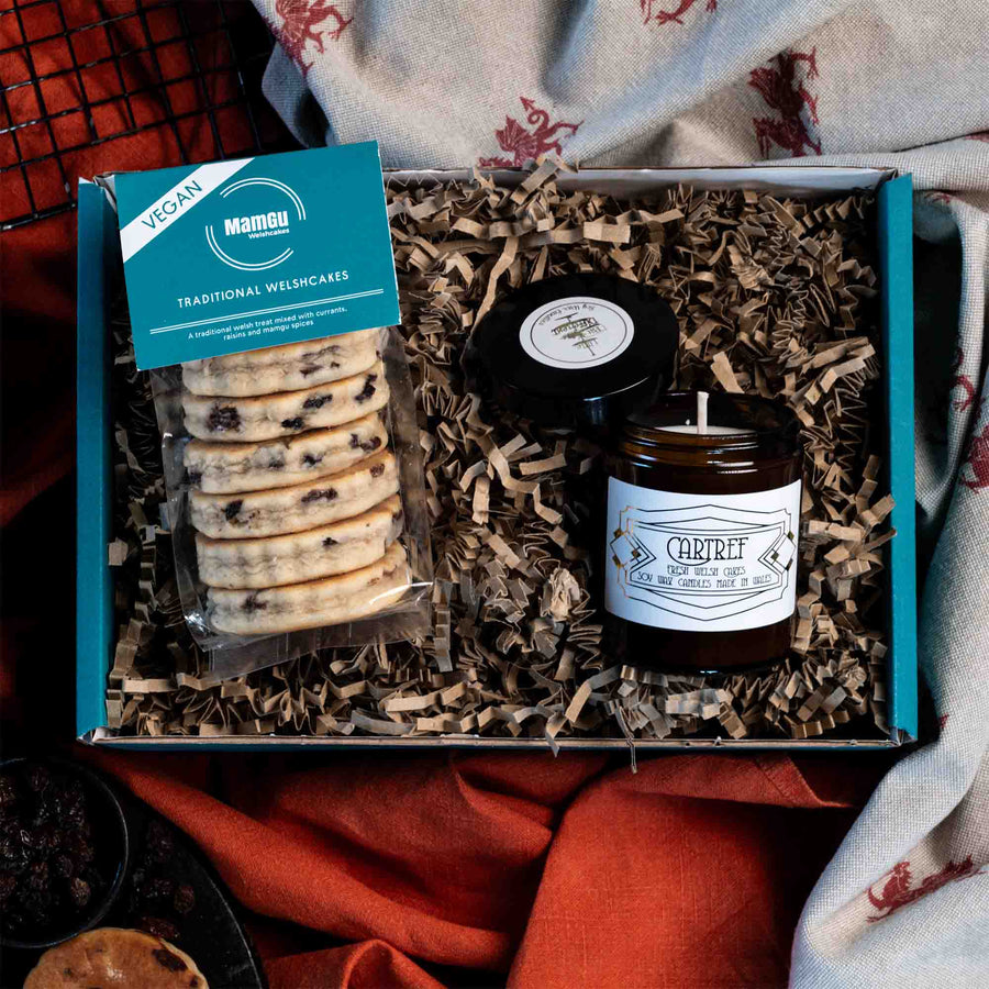 Gift Box with packaged Vegan Traditional Welsh Cakes and a Welsh Cake scented candle displayed on an orange and welsh dragon table cloth