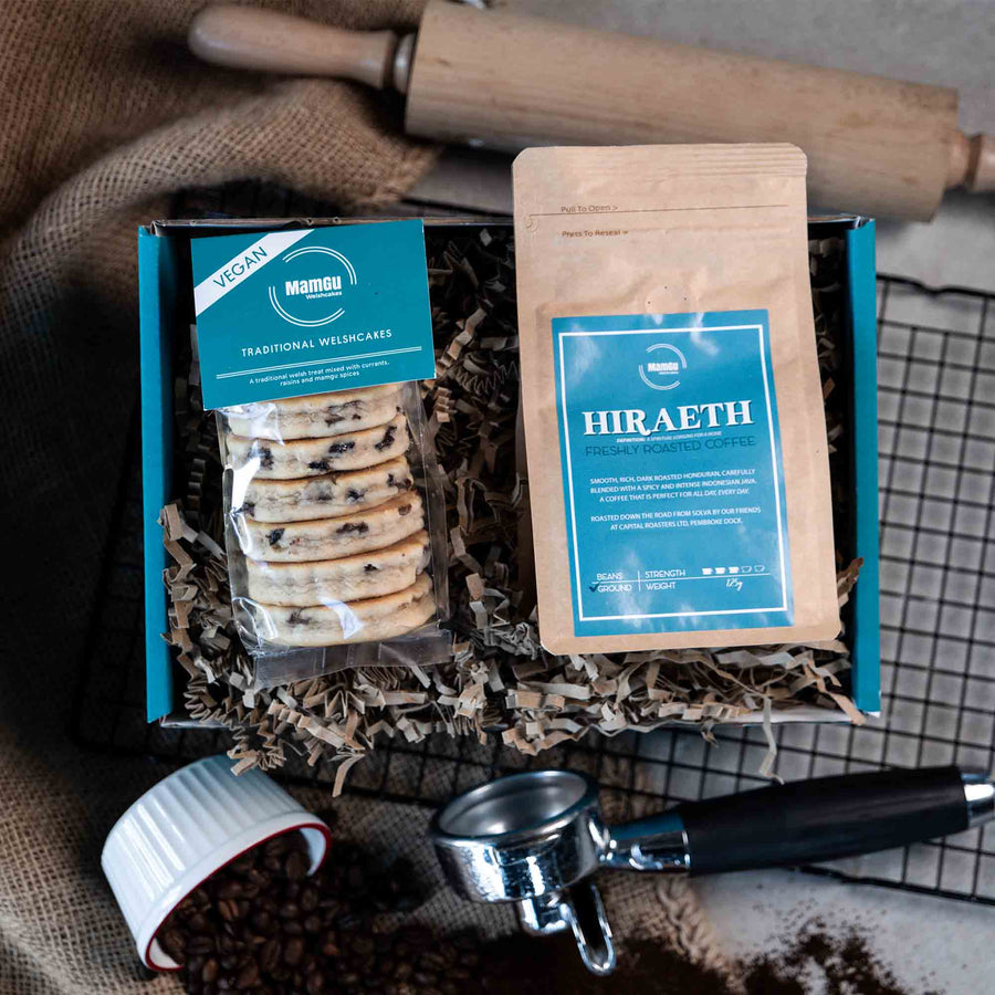 Packaged Traditional Welsh Cakes and ground coffee with branding on a busy kitchen table with rolling pin, cooling rack and coffee beans
