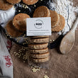 Load image into Gallery viewer, 6 pack of white chocolate chip welsh cakes in clear packaging with a white mamgu welshcakes label. Sitting on a messy rustic kitchen worktop surrounded by ingredients, wooden cutlery and welsh cakes. 
