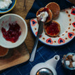 Load image into Gallery viewer, Welsh Cakes with strawberry jam and clotted cream on a decorative plate, surrounded by a bowl of jam and a teapot
