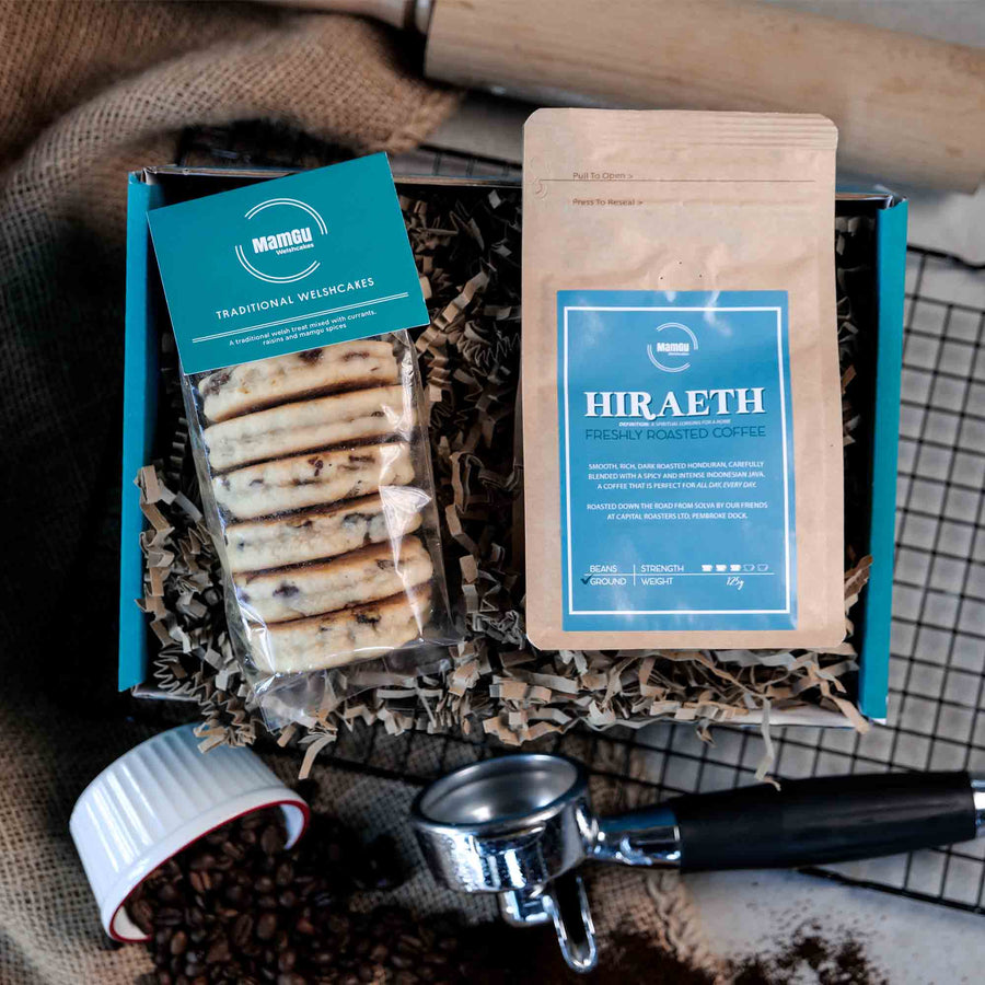 Packaged Traditional Welsh Cakes and ground coffee with branding on a busy kitchen table with rolling pin, cooling rack and coffee beans